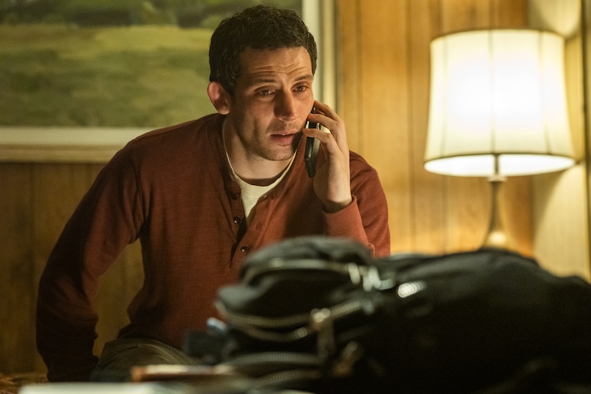 A man sits at a table on a mobile phone.