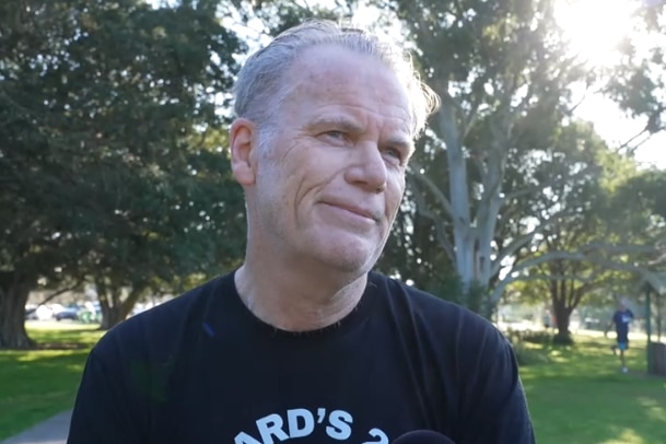 Photo of a man in a black t-shirt looking off to his left side.