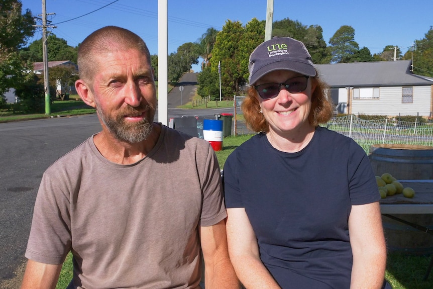 A man and a woman sit smiling in the sun.