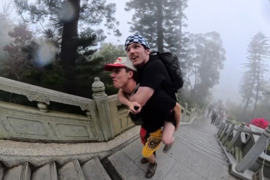 two mates piggybacking up outdoor stairs