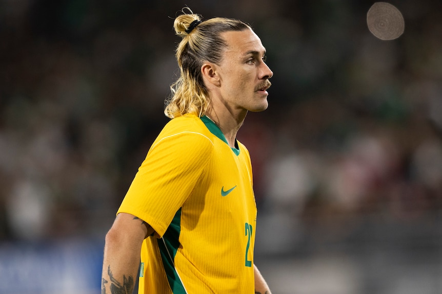 Jackson Irvine stands in the field during a Socceroos game against Mexico.