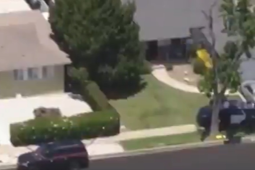 A screen grab from a video taken from a helicopter shows police vehicles parked outside an LA home.