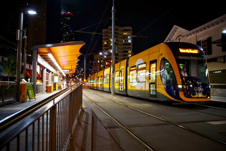 Night time photo of light rail stopped at lit up station