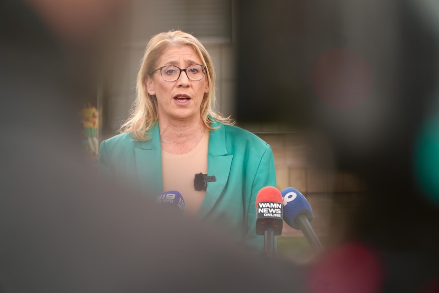 WA Deputy Premier Rita Saffioti speaking into microphones at a media conference outside, wearing a green jacket and biege top.
