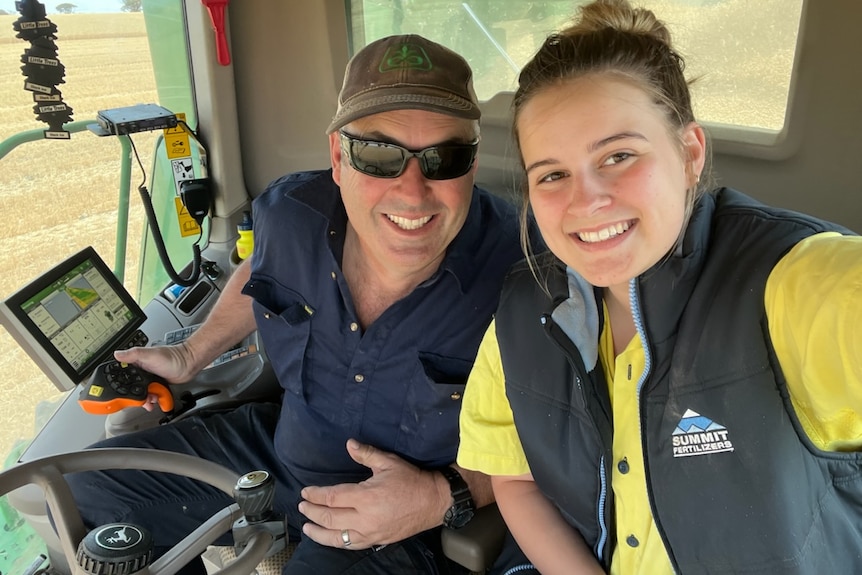 A couple in a harvester machine, smiling