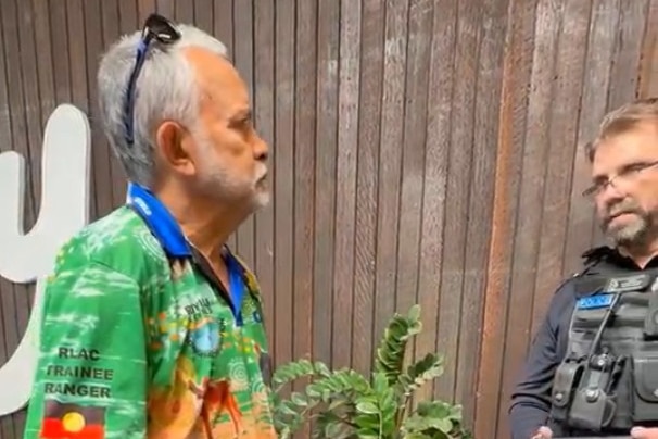 Two men face each other, one wearing a police uniform.