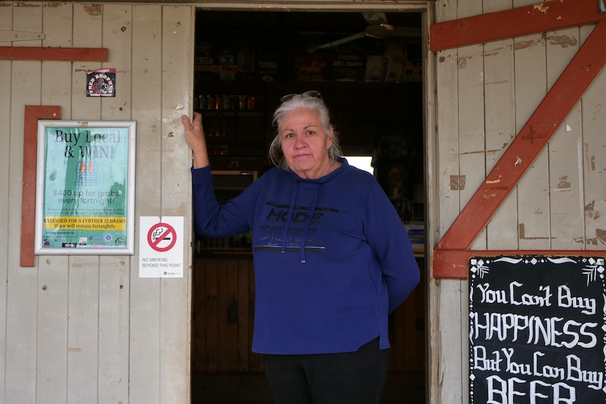 Woman in a blue jumper stands in a doorway at a pub.