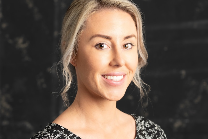 A young blonde, white woman smiling at the camera