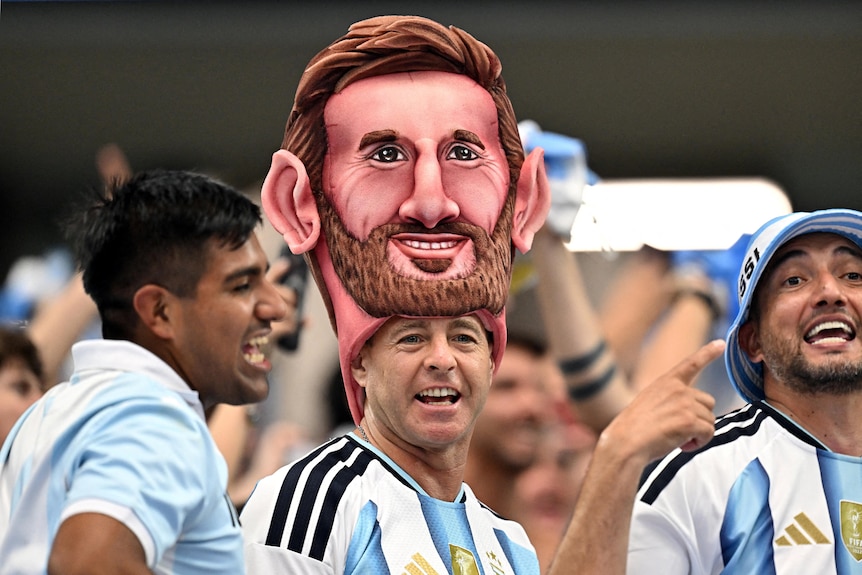 argentinian fans - one wearing a giant lionel messi head atop his own