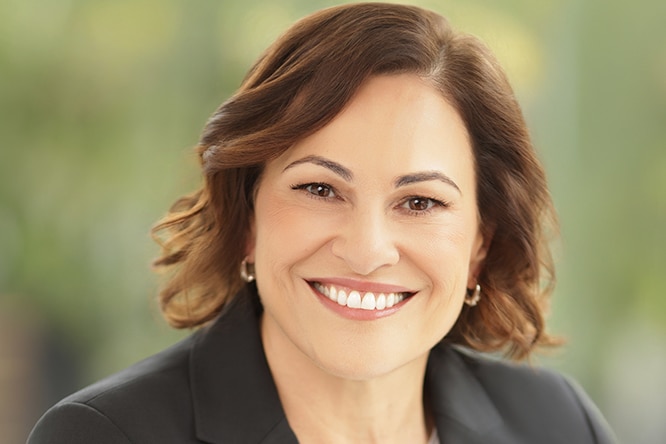 A woman wearing a black jacket smiles for the camera