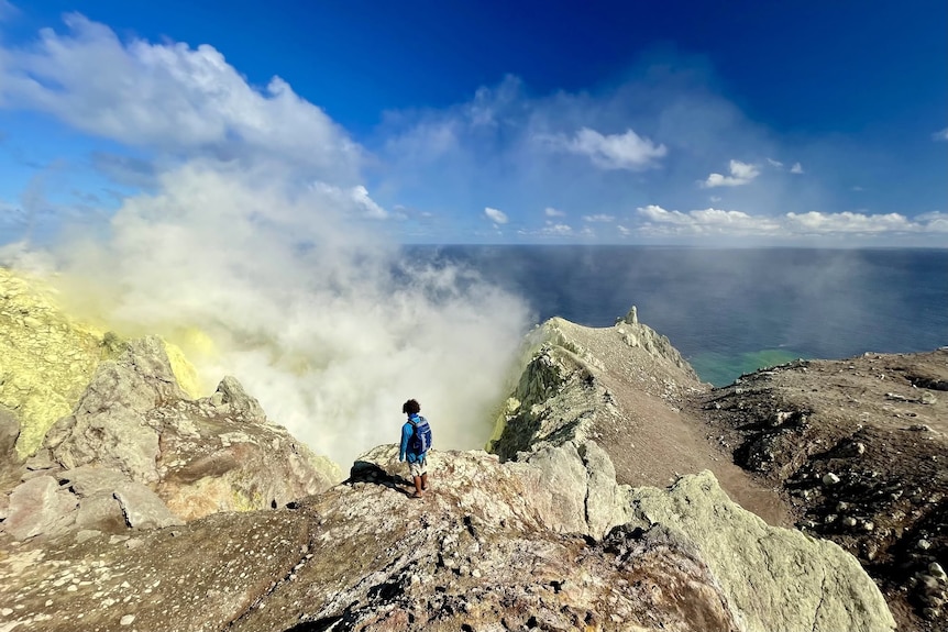 A tourist peers into the vent of the volcano on Matthew Island.