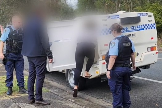 A woman steps into a NSW police van.