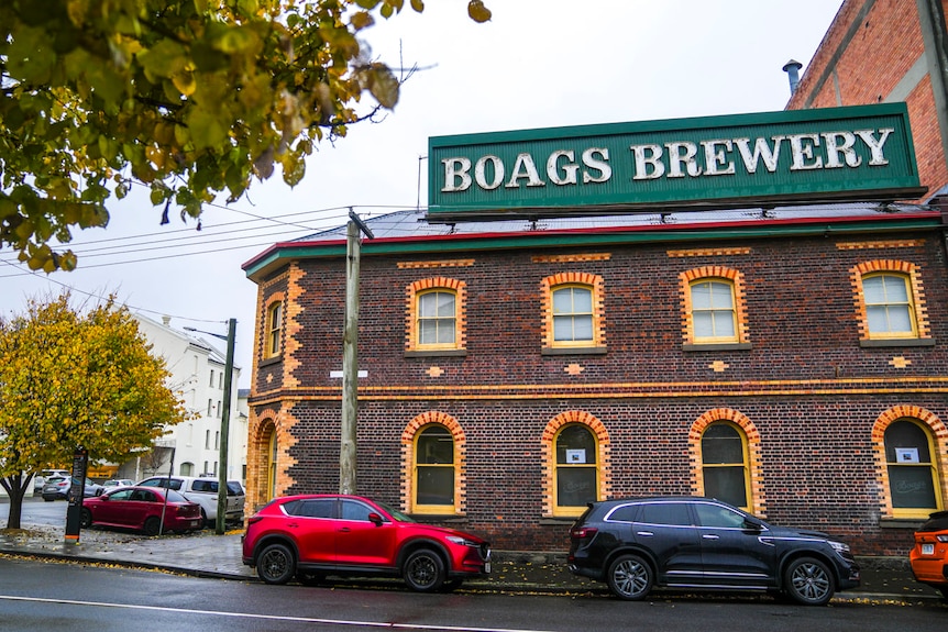 a red brick building with grey skies and green signage