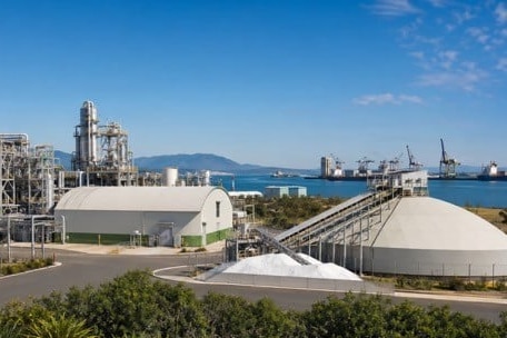 A wide shot of an industrial plant with urea in the foreground and water in the background