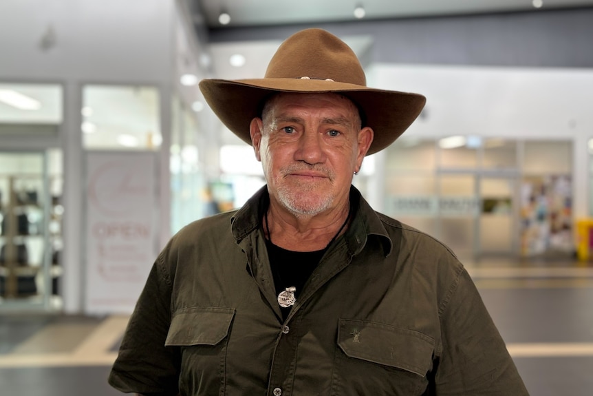 Man in broad-brimmed hat standing in shopping centre