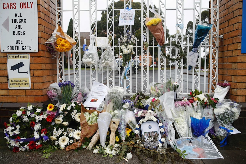 Floral tributes are placed at the gate of the Police Academy for four police officers who died in the line of duty.