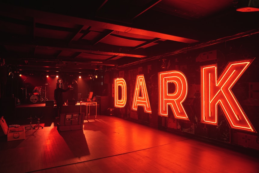 a music venue bathed in red light with a sign reading "dark"