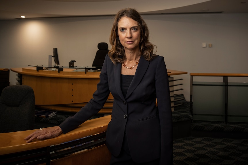 A female coroner standing in her courtroom.