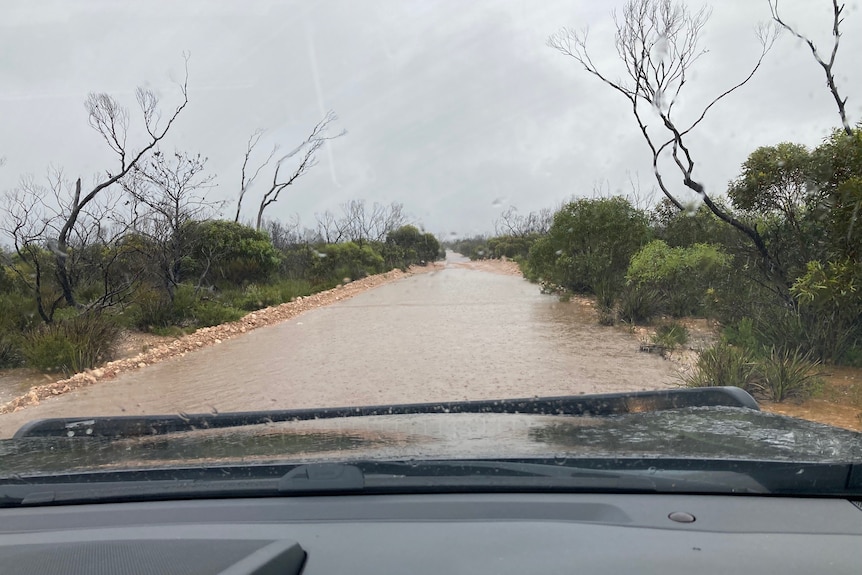 A flooded road seen through the windscreen of a four-wheel drive.