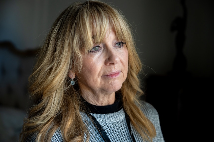 A woman with blonde hair and blue eyes looks off camera