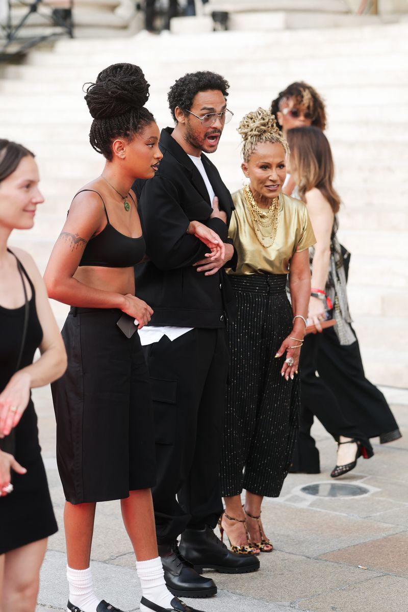 Willow Smith pairs a sculptural braided updo with a minimalist all-black ensemble as she arrives to support brother Jaden Smith at Christian Louboutin's Paris Fashion Week show.