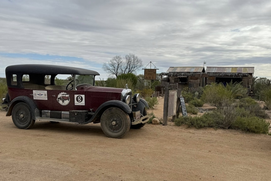 A maroon Studebaker is parked in front of the historic Coward Springs building.