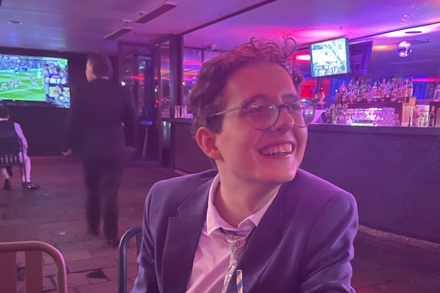 A young man with glasses sitting in a restaurant.
