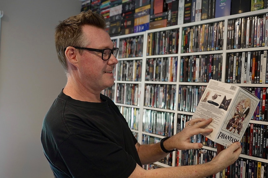 Man in black tee-shirt looking at video and DVD collection