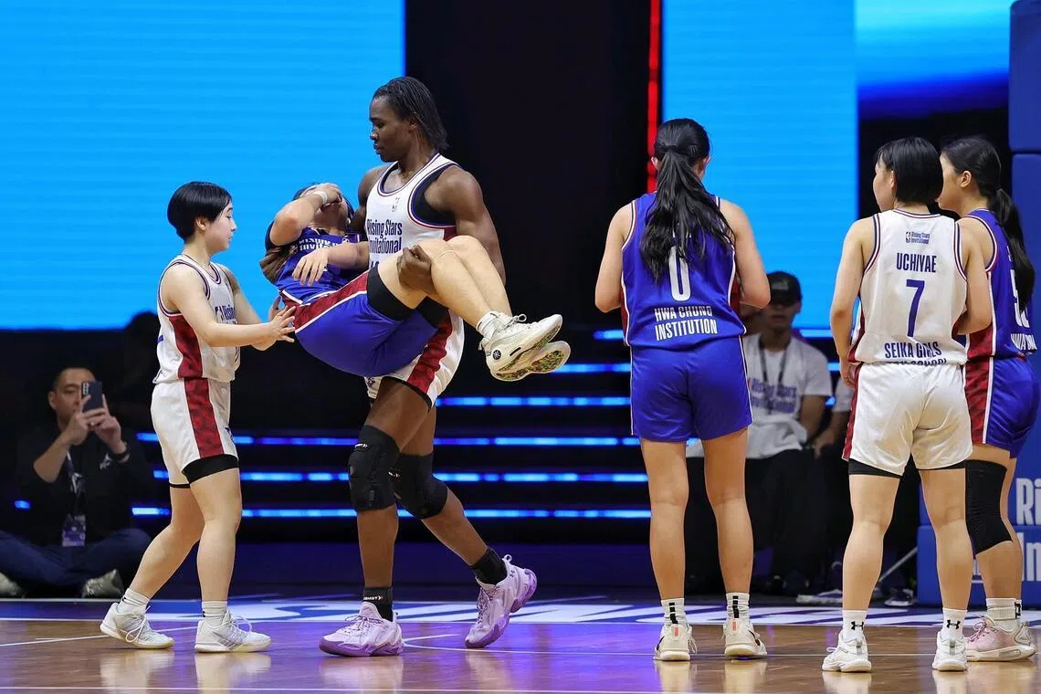 Buba Aisha Ezzine of Seika Girls’ High School carrying Karis Lau of Hwa Chong Institution to the bench in an act of sportsmanship after injuring the latter in their NBA Rising Stars Invitational group stage match at OCBC Arena on June 24, 2026.
