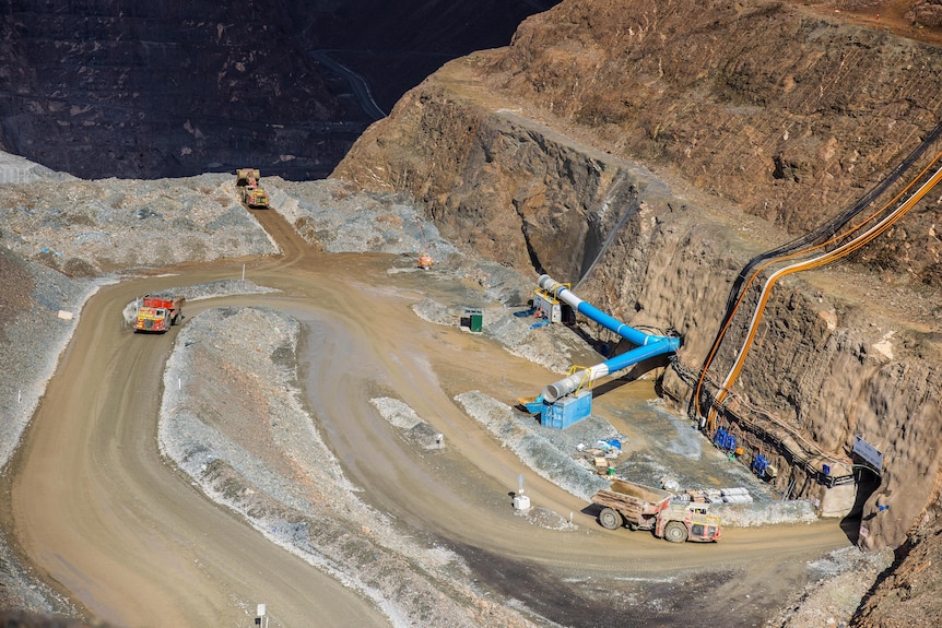 Trucks moving in and out of an underground access portal at a gold mine.
