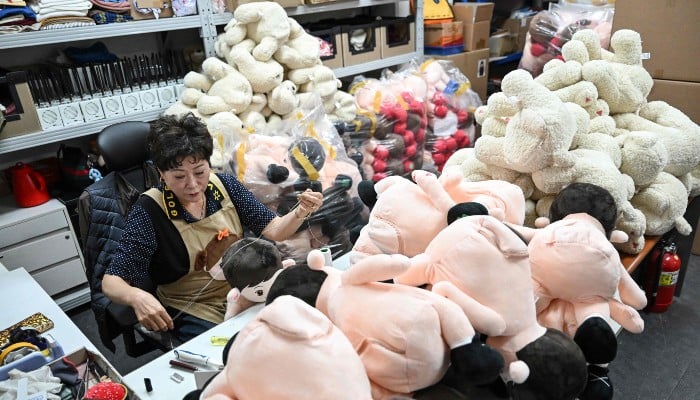 This picture taken on May 6, 2026, shows a worker sewing a Hyodol, an AI-powered healthcare doll designed for elderly people, at the companys headquarters in Anyang, South Korea. — AFP