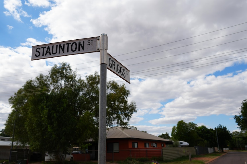 A two-street sign post that reads 'Staunton St' and 'Griggs St' with houses and street visible in background.