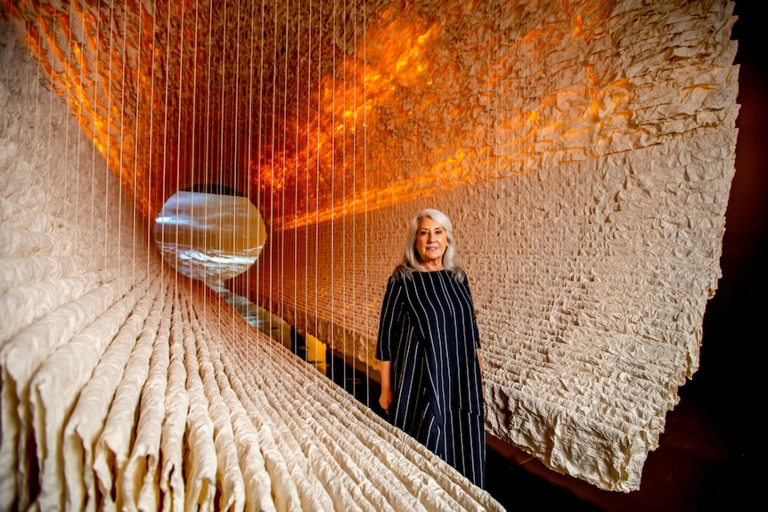 The arts patron standing inside a huge cylinder made of rows of rice paper.