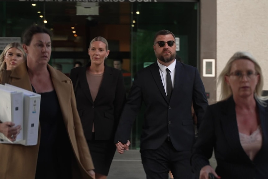 A group of people in suits walk away from a building.
