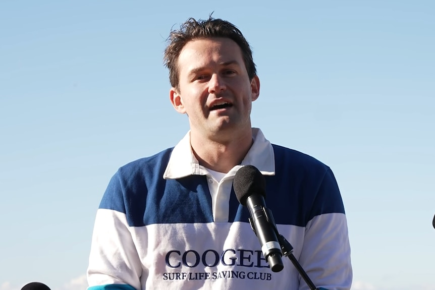 Mr Heenan wearing a striped rugby jumper with 'Coogee Surf Life Saving Club' on it speaking to media.