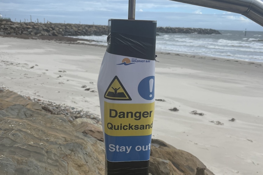 An A4 paper sign stuck to a pole the reads "danger quicksand" and "stay out"