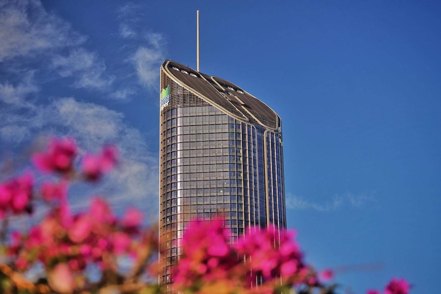 Top of 1 William Street building in Brisbane CBD, taken from South Bank with bougainvillea flowers in the foreground.