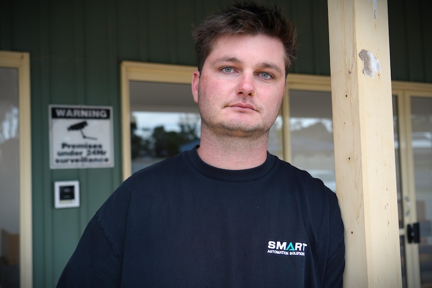 man stares at the camera with security sign behind him