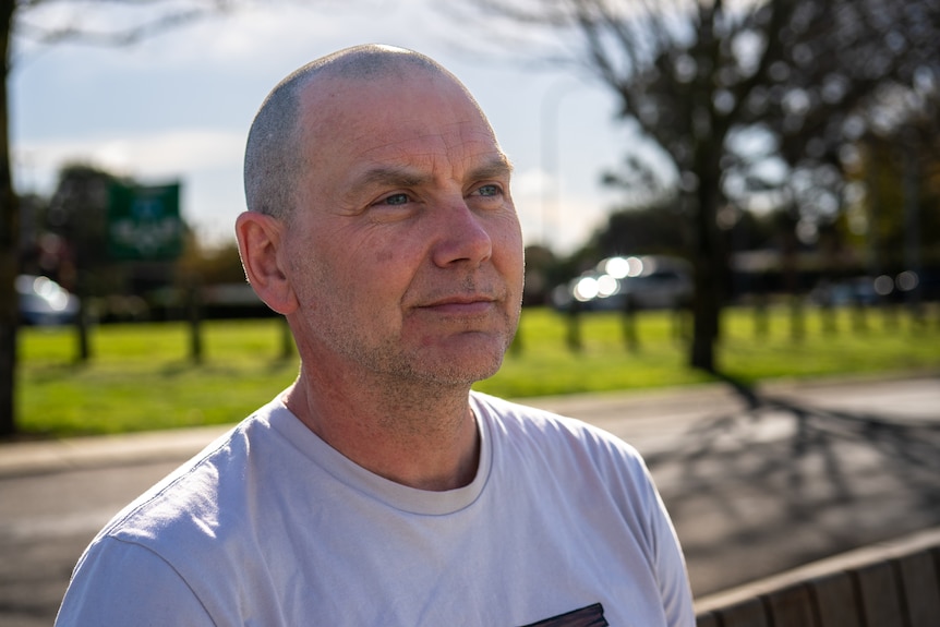 Profile of a man sitting on a bench.