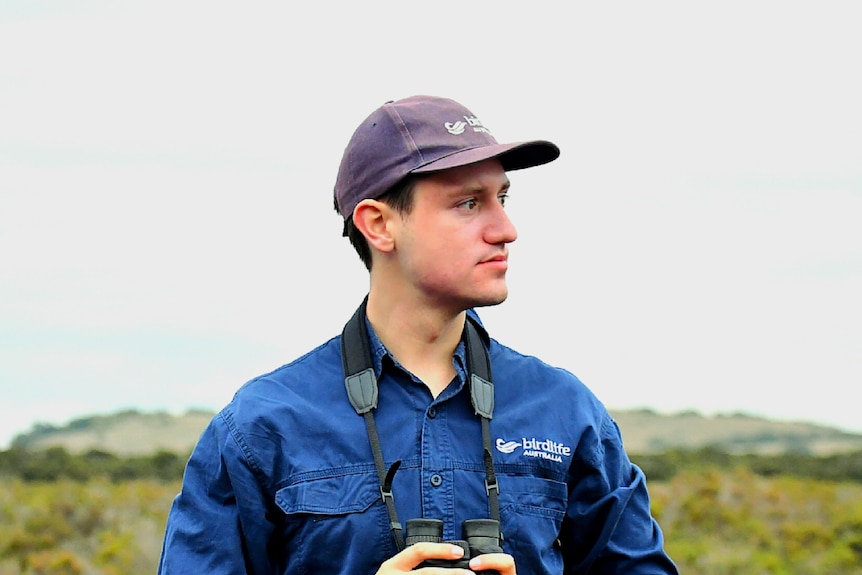 Man in wetlands with binoculars.