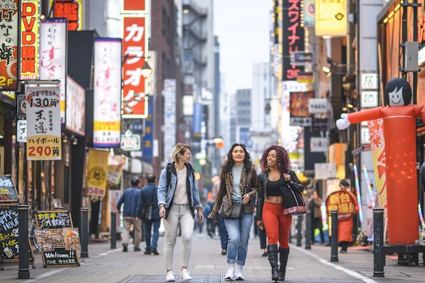 female tourists walking together through Shinjuku in Tokyo at dusk.