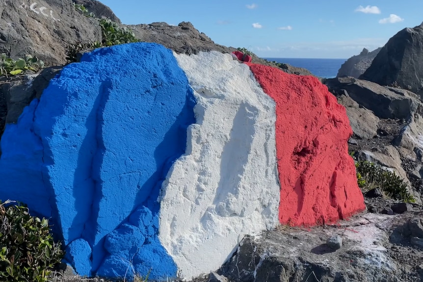 A rock painting in the colours of the French flag.