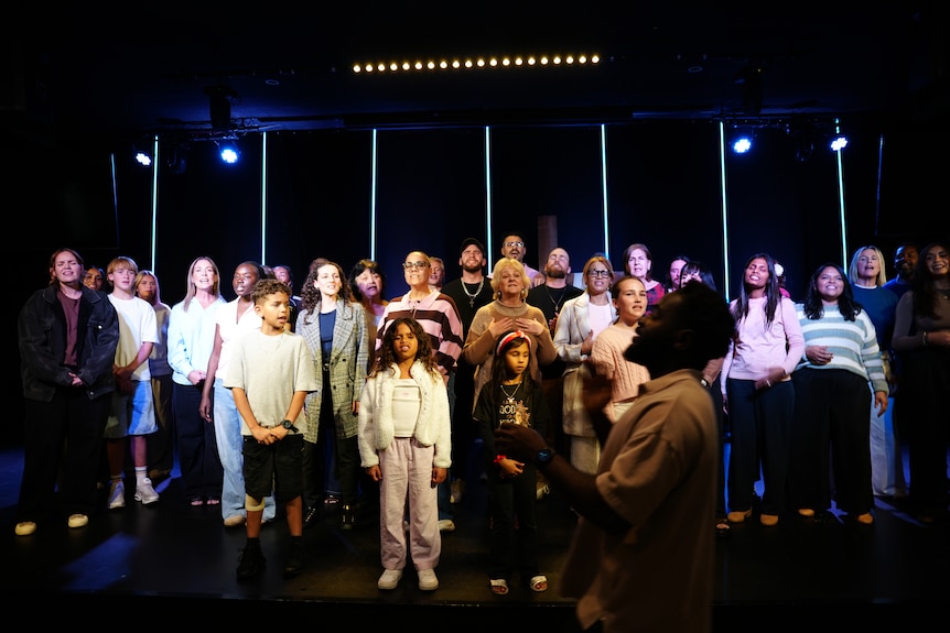 A choir rehearses under lights.