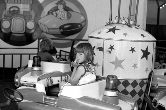 A young girl on a ride at Luna Park, Melbourne, has a pensive moment, 1977.