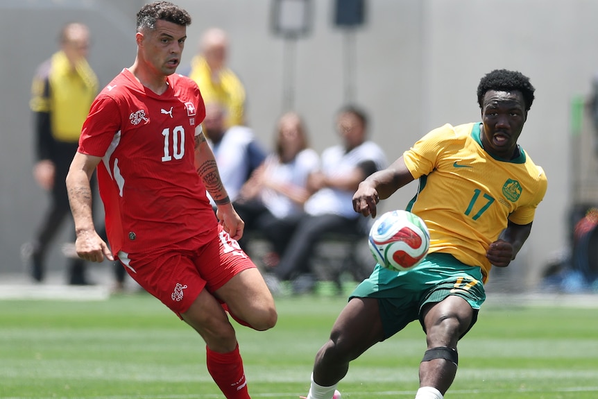 Nestory Irankunda of Australia competes for the ball against Granit Xhaka of Switzerland.