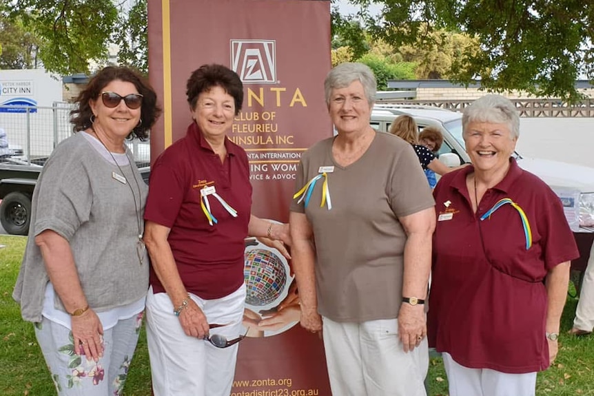 Four women pose with a Zonta banner
