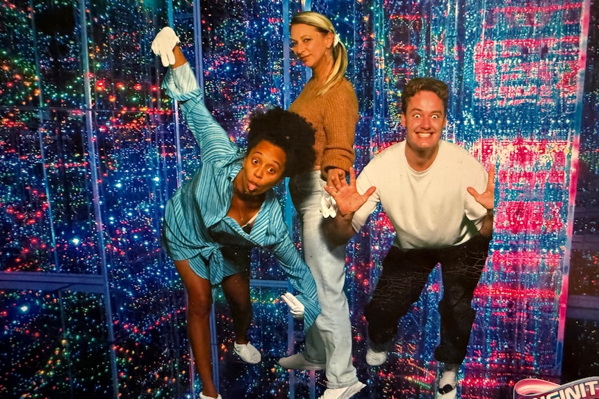 Two women and a man in a light-filled sensory room at a funhouse.