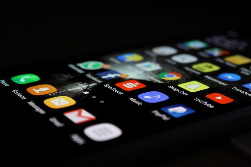 A black iphone screen with apps, sitting horizontally.