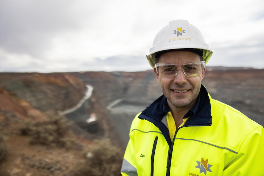 A geologist in a hard-hat wearing high-vis at a gold mine.
