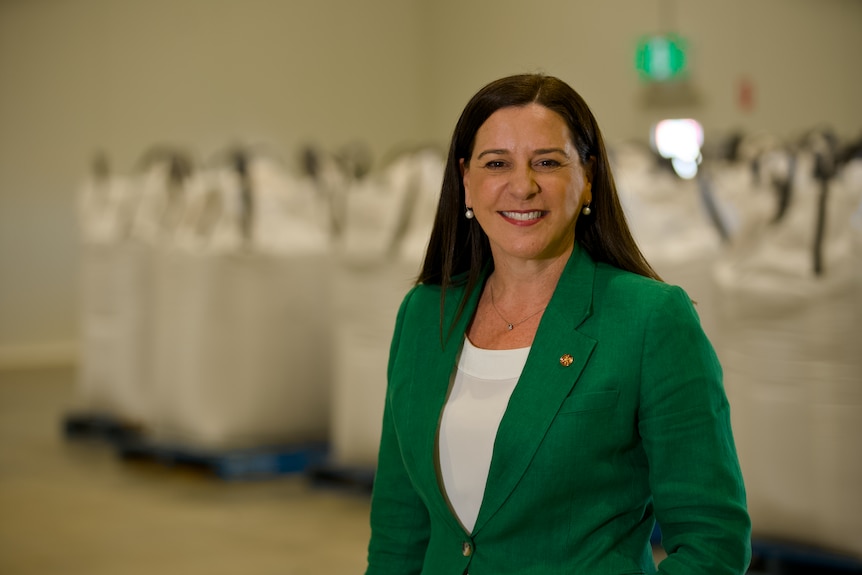 A woman with brown hair wearing a green blazer.